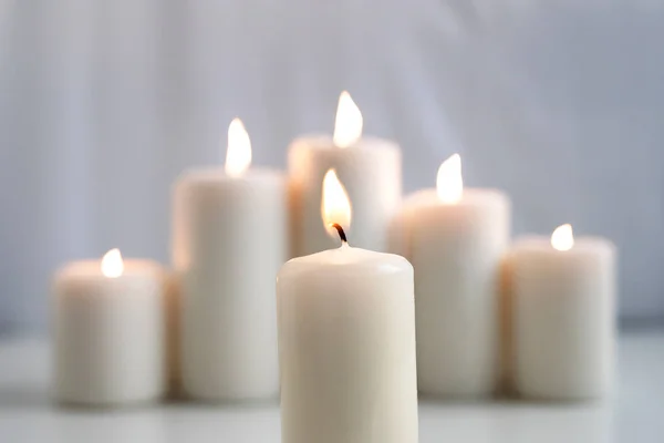 stock image Large burning wax candles on a white background.