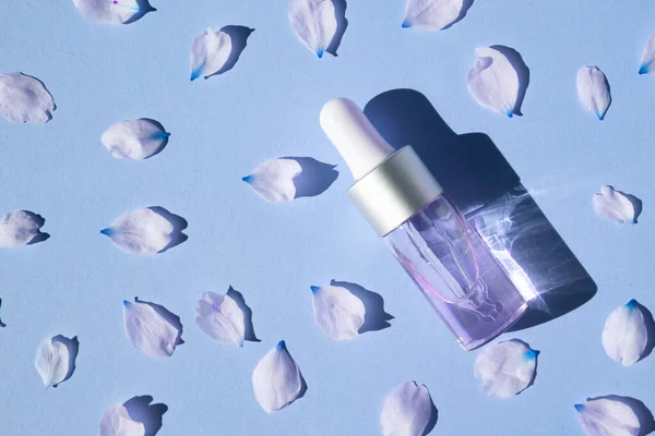 Purple bottle with cosmetic gel on a light purple background with rose petals.