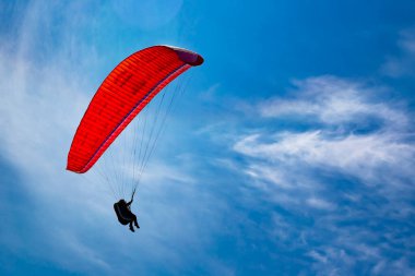 Bir paraglider mavi gökyüzünde uçuyor. Güneşli bir günde paraşütle atlamak.