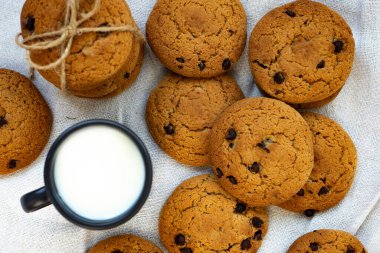 Ev yapımı yulaf ezmeli kurabiyeler, çikolata damlaları ve bir fincan taze süt. Yukarıdan görüntüle.