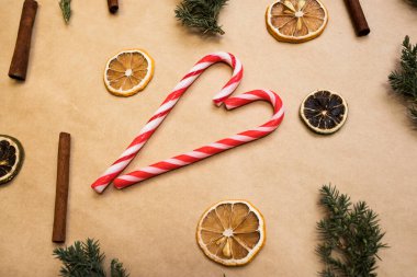 Noel kompozisyonu. Turuncu dilimler, tarçın ve ladin dallarıyla Kraft kağıdında kalp şeklinde çizgili karamel..