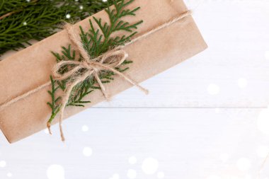 El işi kağıt hediye kutusu ve beyaz ahşap arka planda köknar dalları. Üst görünüm, metin için yer.