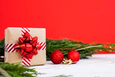 Noel hediyesi olarak arkaplanda kozalaklı dallar ve parlak toplar var..