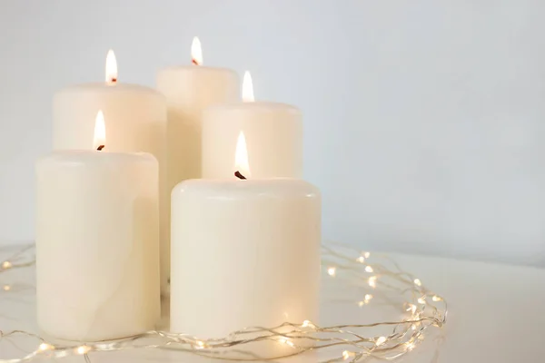 Büyük yanan mumlar ve beyaz bir arka planda Noel çelengi. Yan görünüm, metin için boşluk.