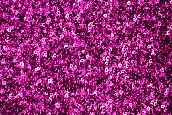 Shiny pink fabric texture with metallic sequins. Flat lay, close-up.