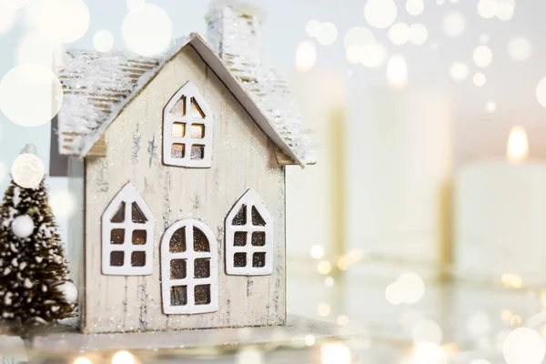 A toy house on the background of burning candles. Accessories on Christmas Day and New Year\'s Day. Christmas background.