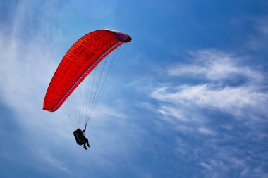 Bir paraglider mavi gökyüzünde uçuyor. Güneşli bir günde paraşütle atlamak.