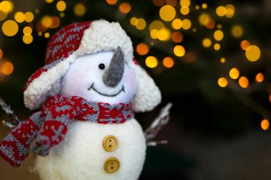 Oyuncak kardan adam Noel ışıklarının arka planında.