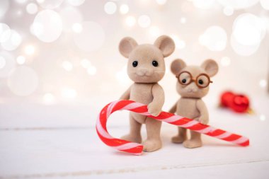 Şirin komik fareler bulanık arkaplanda çizgili karamel tutarlar. Yeni yıl kompozisyonu. Yan görünüm, metin için yer.