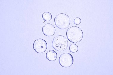 Katı bir arka planda şeffaf bir kozmetik ürününün damlaları. Düz yatıyordu. 2022 Yılının Moda Rengi.