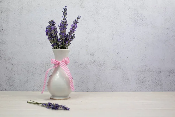 Fresh lavender bouquet in vase on gray background.