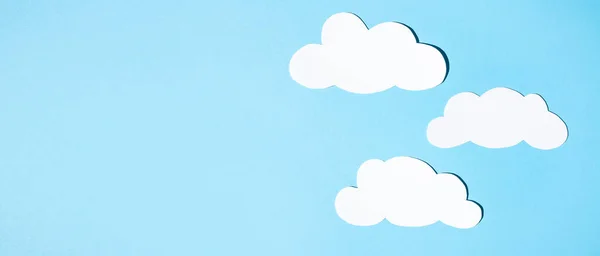 stock image Silhouettes of clouds from white paper on a blue background. Banner, flat lay, place for text.