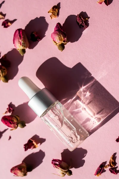 玻璃水瓶与清澈的凝胶液体和天然玫瑰投下的阴影粉红色背景 有机化妆品 垂直图像 — 图库照片