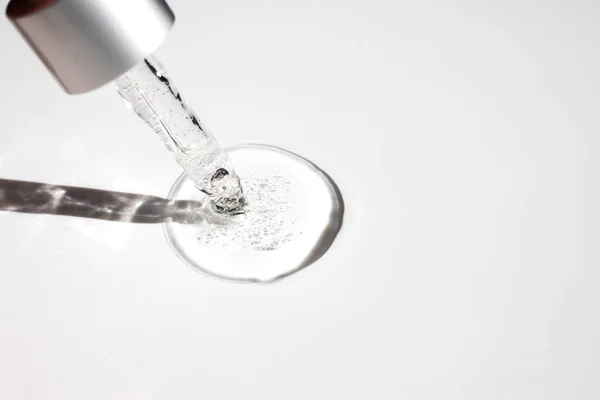 Kabarcıklı şeffaf jel benzeri bir sıvı ve gri arka planda bir pipet. Üst görünüm, metin için yer.
