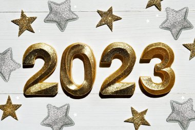 Geçmiş şenlik 2023 'ün kutlu olsun. Beyaz ahşap arka planda 2023 numaralı altın parıltı. Yan görünüm, yakın plan.