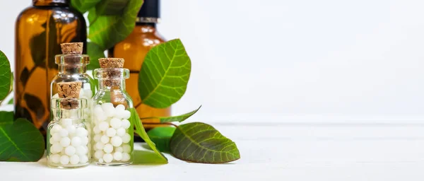 Beyaz arka planda küçük cam şişelerdeki homeopatik küreseller. Homeopati konsepti. Yan görünüm, metin alanı.