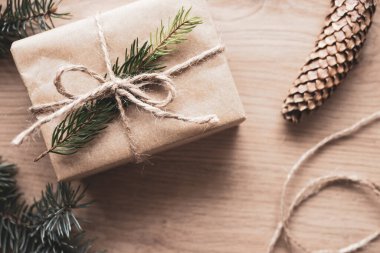 Tahta arka planda doğal ladin dalı olan Kraft kağıdında noel hediyesi. Üst görünüm, metin için boşluk.