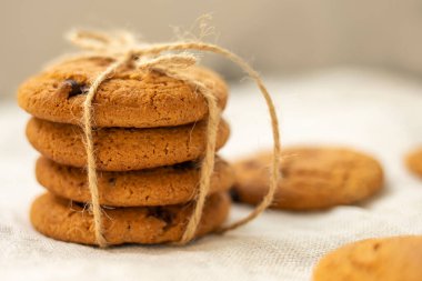 Taze ev yapımı çikolatalı kurabiyeler, tuvalin arka planında jüt ile bağlanmış. Yan görünüm, yakın plan.