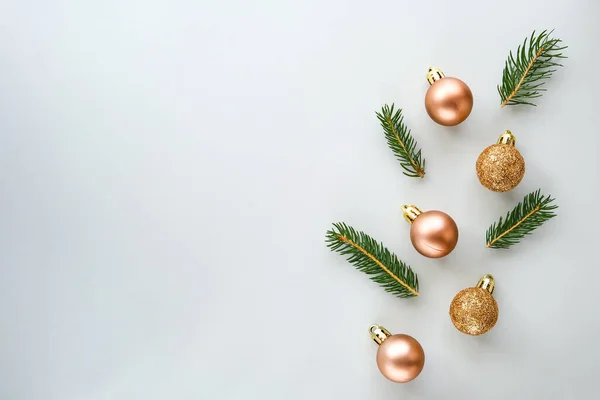 Christmas composition. Christmas glitter balls and natural spruce branches on gray background. Flat lay, top view, copy space.
