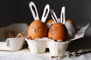 Easter eggs with a funny bunny's face and ears in an egg cage. Side view, close-up. Easter concept.