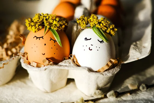 Easter eggs with a funny face and a wreath of flowers in an egg cage. Side view, close-up. Easter concept.