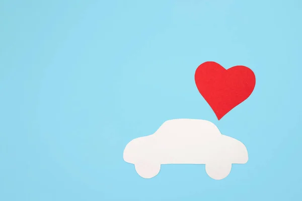 Silhouette of a car with a big red heart on a blue background. Flat lay, place for text.