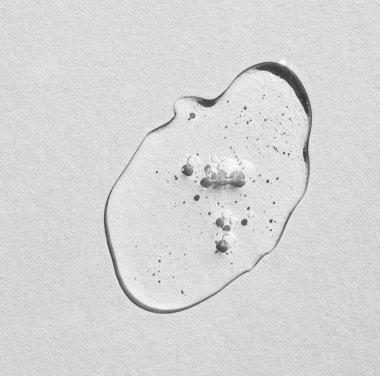 Gri arka planda köpükler olan şeffaf nemlendirici kozmetik jel damlası. Düz yatış, metin için yer.