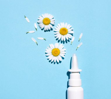 Mavi arka planda beyaz plastik burun spreyi paketi. Mevsimsel alerji tedavisi. Üst görünüm, metin için boşluk.