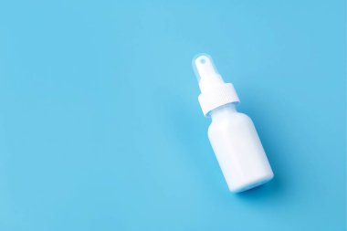 Mavi arka planda beyaz plastik burun spreyi paketi. Mevsimsel alerji tedavisi. Üst görünüm, metin için boşluk.
