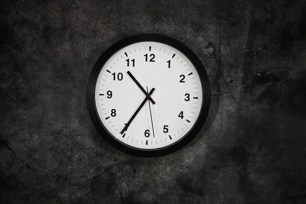Round modern clock on a black background.