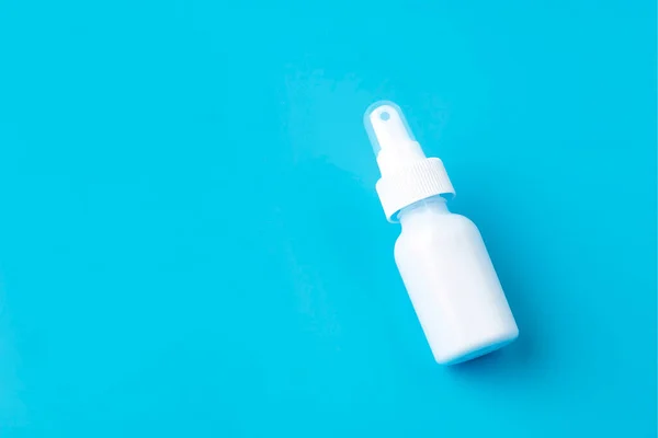 White plastic package of nasal spray on a blue background. Treatment of seasonal allergies. Top view, space for text.