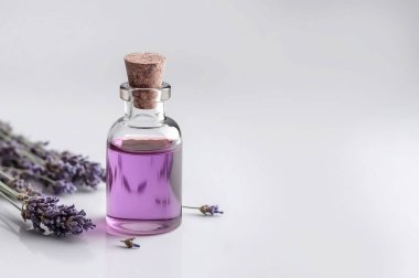 Aromaterapi için gerekli yağ şişeleri, alternatif tıp ve hafif arkaplanda taze lavanta çiçekleri.