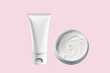 Cilt bakım ürünlerini damgalamak için beyaz plastik bir tüp ve pembe arka planda bir kavanoz nemlendirici krem. Düz konum, üst görünüm, kopyalama alanı.