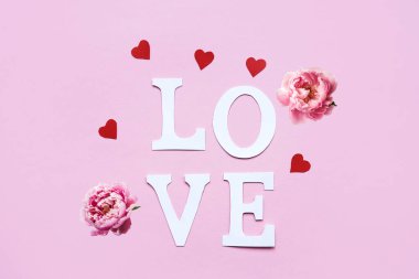 Kağıt harflerden kelime sevgisi ve pembe arka planda kırmızı kalpler. Düz yatış, metin için yer.
