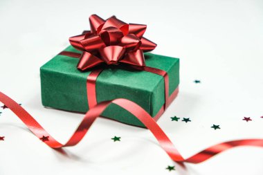 Beyaz arka planda kırmızı ipek kurdeleli bir hediye kutusu ve bir sürü parlak konfeti. Mutlu yıllar ve mutlu Noeller..