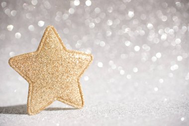 Işıl ışıl gri arka planda altın parıldayan yıldız şeklinde bir Noel dekoru. Yan görünüm, metin için boşluk.