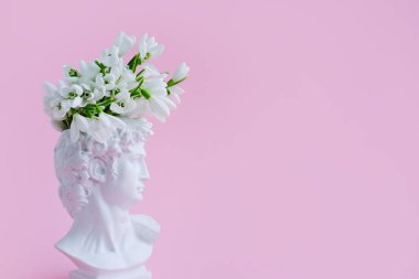 David 'in başının beyaz alçı heykeli ve pastel pembe arka planda kardamlaları. Metin için alanı olan yaratıcı pankart.