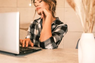 Kadın bir serbest çalışan mutfaktaki dizüstü bilgisayarını ofis olarak kullanıyor..