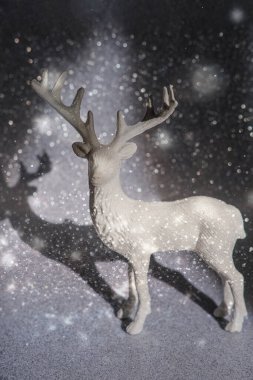 Işıltılı karlı arkaplanda geyik heykeli