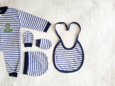 Bebek geçmişi. Beyaz masadaki yeni doğan çocuk için giysi ve aksesuarlar..