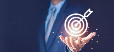 Ticari hedef kavramını oluşturmak için sanal dart tahtası ve oku elinde tutan işadamı.