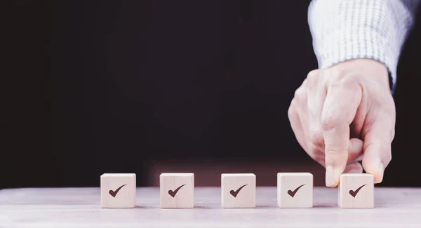 stock image Checklist Survey and assessment concept, human hand putting cube wood with Check mark icon on wooden blocks, gray background with copy space