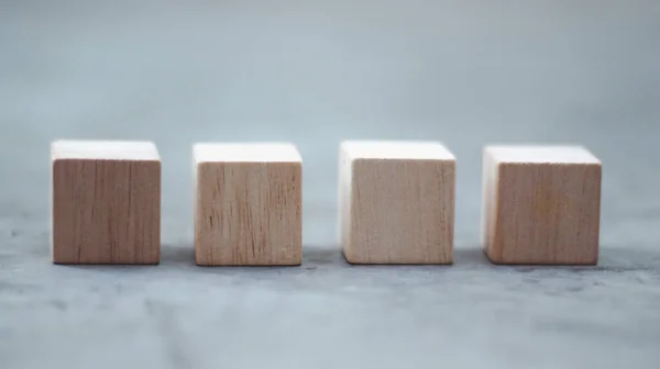 Four wooden cubes laying on gray background
