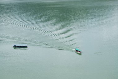 Suda yeşil gölgelikli bir tekne var.