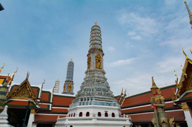 Ortasında uzun bir kule olan büyük bir bina. Bina daha küçük binalarla çevrili ve birçok dekorasyonu var. Gökyüzü açık ve mavi