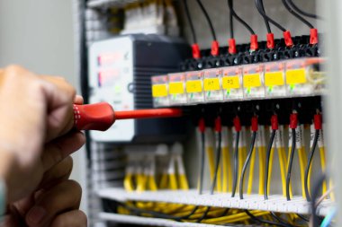 Elektrik tesisatçısı elektrik kabinesi kontrolünde voltaj ve elektrik akımını ölçen bir testçi, Profesyonel adam koruma sistemi için araç görevlendirme testi veya kontrol devresi kullanıyor.