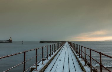 Kuzey Denizi 'ne uzanan eski ahşap iskeledeki Blyth sahilinde dondurucu, karlı bir sabah
