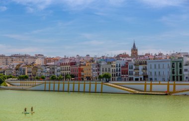 The view across the Canal de Alfonso XIII (translated to Alfonso XIII Canal), towards the district of Triana and the famous colorful Calle Betis (translated to Betis Street) in Seville, Spain clipart