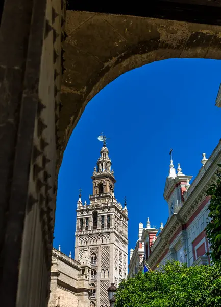 stock image La Giralda (translated to The Giralda), the bell tower of Seville's Cathedral taken through an old doorway, Spain