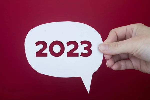 Speech bubble in front of colored background with the number 2023.